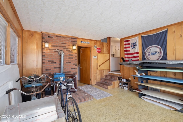 interior space featuring a wood stove, an ornate ceiling, wooden walls, and stairway