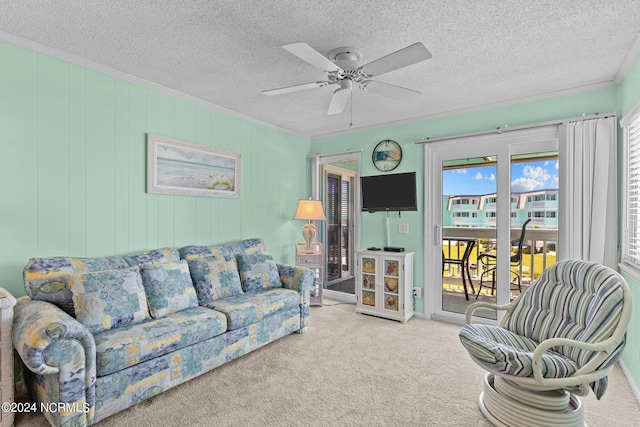 carpeted living room featuring ceiling fan, a textured ceiling, and crown molding