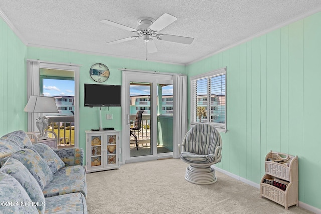 sitting room featuring a textured ceiling, carpet flooring, a ceiling fan, and crown molding