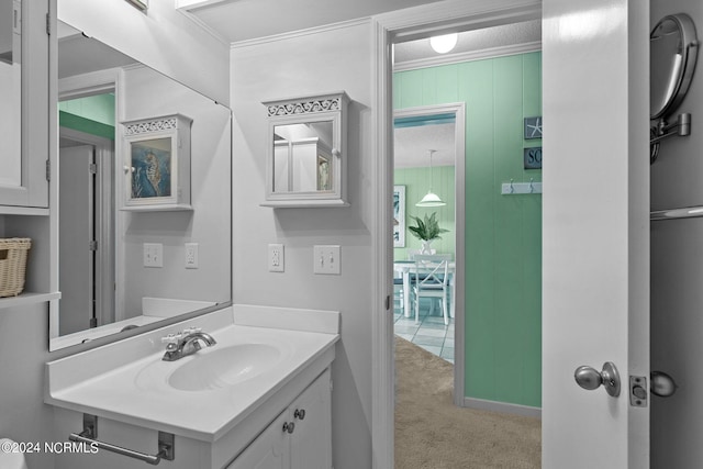 bathroom with wood walls, crown molding, and vanity