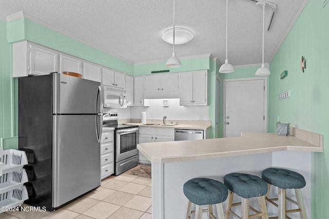 kitchen with a peninsula, appliances with stainless steel finishes, white cabinets, and a sink