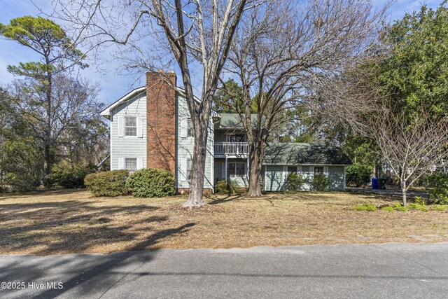 rear view of property featuring a chimney and a balcony