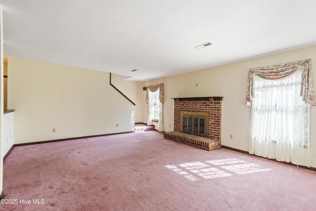 unfurnished living room featuring baseboards, visible vents, a textured ceiling, carpet flooring, and a fireplace