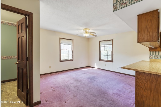 unfurnished living room with baseboards, light colored carpet, and a healthy amount of sunlight