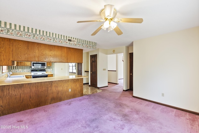 kitchen featuring carpet flooring, a sink, electric stove, brown cabinets, and stainless steel microwave