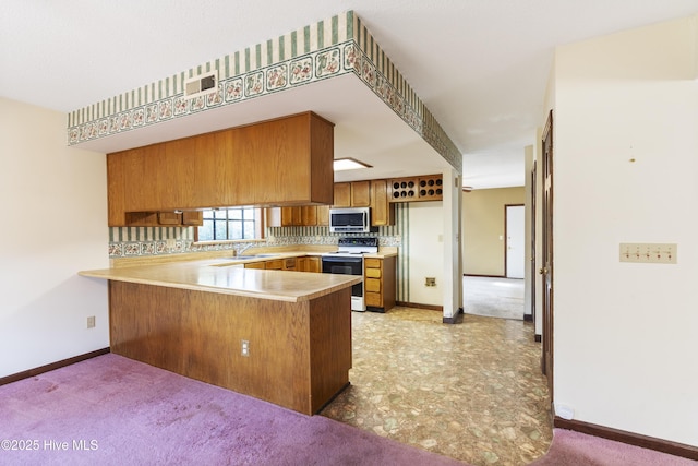 kitchen featuring a peninsula, light countertops, brown cabinets, stainless steel microwave, and white electric range oven