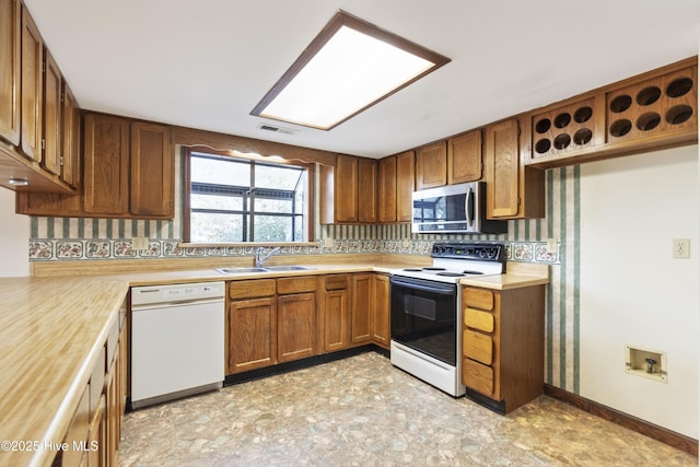 kitchen featuring white dishwasher, range with electric cooktop, a sink, light countertops, and stainless steel microwave