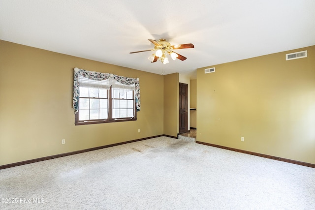 carpeted spare room featuring baseboards, visible vents, and a ceiling fan