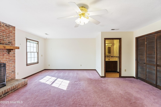 unfurnished living room featuring ceiling fan, carpet flooring, visible vents, baseboards, and a brick fireplace