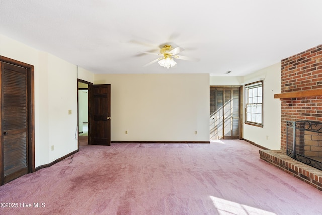 unfurnished living room featuring a brick fireplace, carpet flooring, ceiling fan, and baseboards