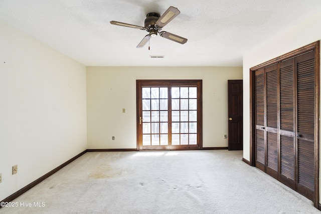 unfurnished bedroom with a closet, light colored carpet, visible vents, a textured ceiling, and baseboards