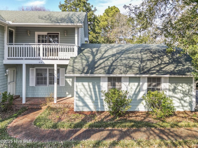 view of side of property with a balcony and roof with shingles