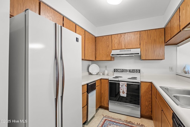 kitchen with electric range, exhaust hood, freestanding refrigerator, dishwasher, and brown cabinetry