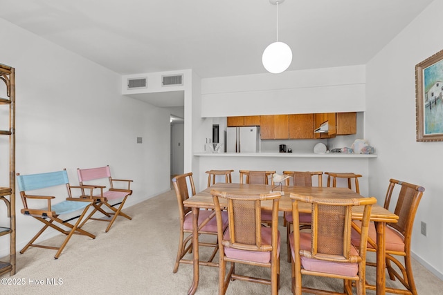 dining room featuring baseboards, visible vents, and light colored carpet