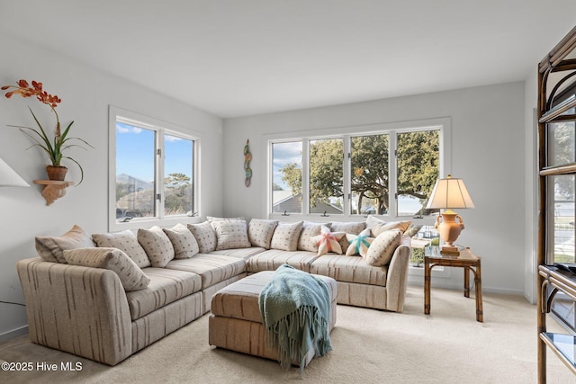 living area with baseboards, a wealth of natural light, and light colored carpet