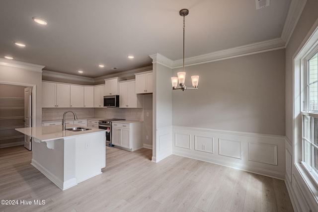 kitchen featuring light wood finished floors, backsplash, a sink, stainless steel appliances, and a notable chandelier