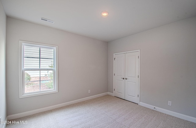 empty room featuring carpet flooring, visible vents, and baseboards