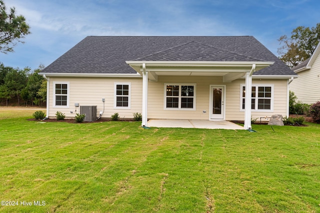 rear view of property featuring a patio, a shingled roof, a lawn, and central AC unit