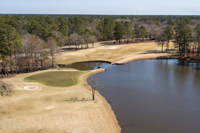 drone / aerial view featuring view of golf course, a water view, and a wooded view