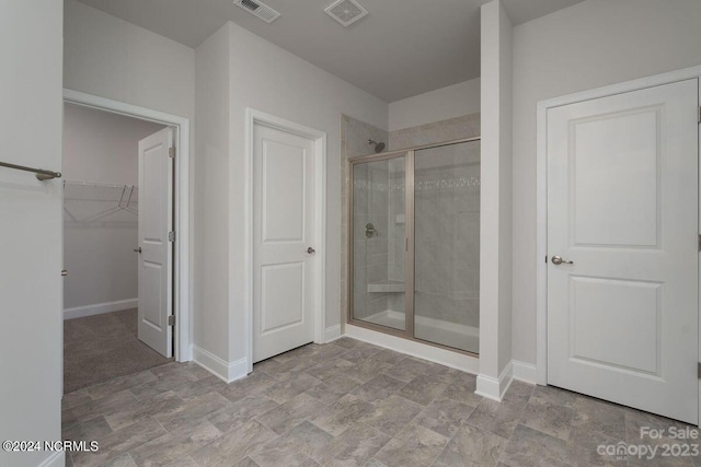 full bath with baseboards, a shower stall, visible vents, and a walk in closet