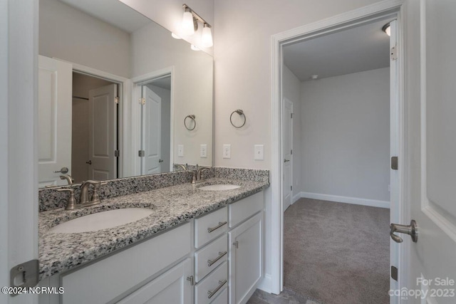 full bathroom with double vanity, baseboards, and a sink