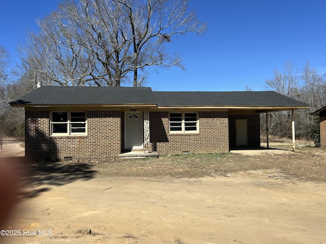 view of front of home with brick siding, a shingled roof, driveway, crawl space, and a carport