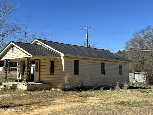 view of side of home featuring a porch and metal roof