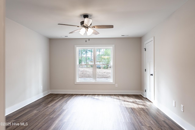 unfurnished room with dark wood-type flooring, visible vents, and baseboards