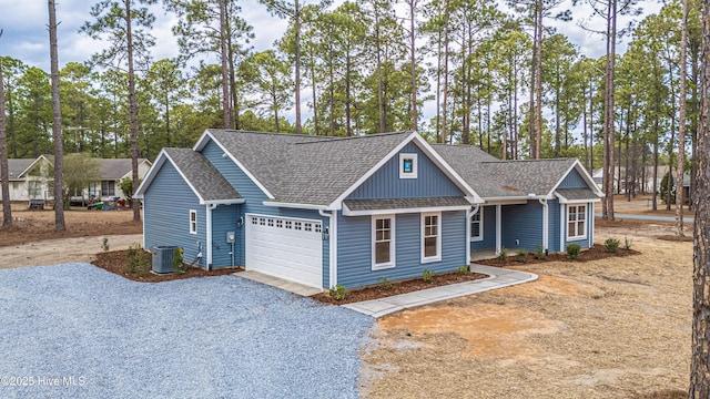 view of front of house with a garage, driveway, central AC unit, and roof with shingles