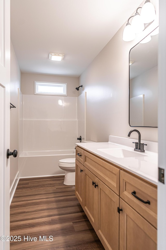 bathroom with shower / bath combination, toilet, wood finished floors, and vanity