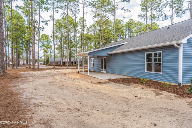 exterior space with a shingled roof and a patio area