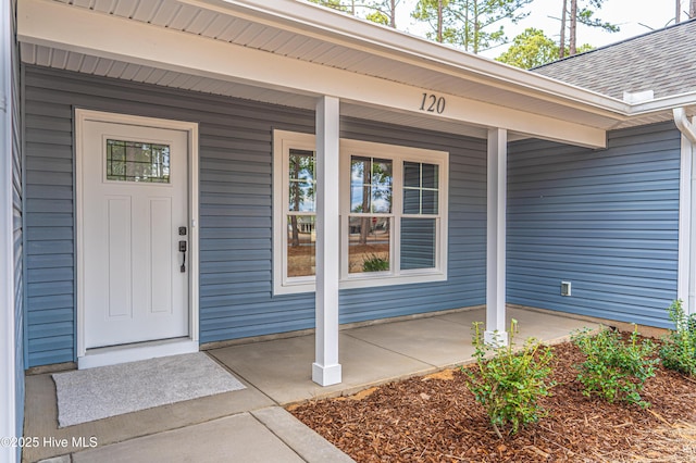 entrance to property with covered porch and roof with shingles