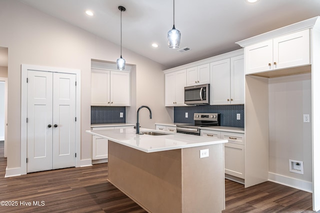 kitchen with lofted ceiling, appliances with stainless steel finishes, dark wood-type flooring, white cabinetry, and a sink