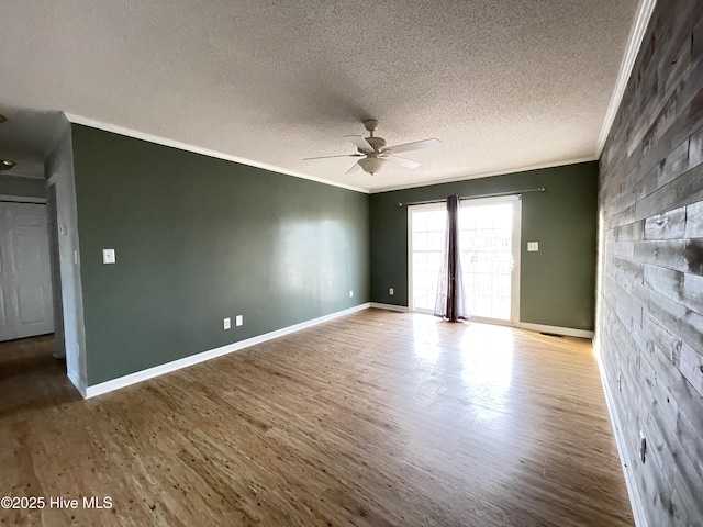 empty room with baseboards, ceiling fan, ornamental molding, and wood finished floors