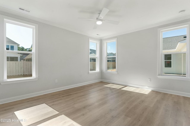 unfurnished room featuring visible vents, light wood-style flooring, ornamental molding, a ceiling fan, and baseboards