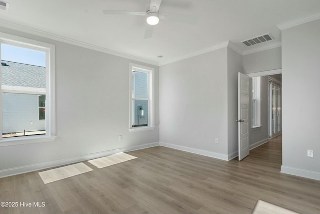 empty room with visible vents, crown molding, baseboards, and wood finished floors