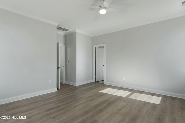 spare room featuring wood finished floors, visible vents, a ceiling fan, baseboards, and ornamental molding