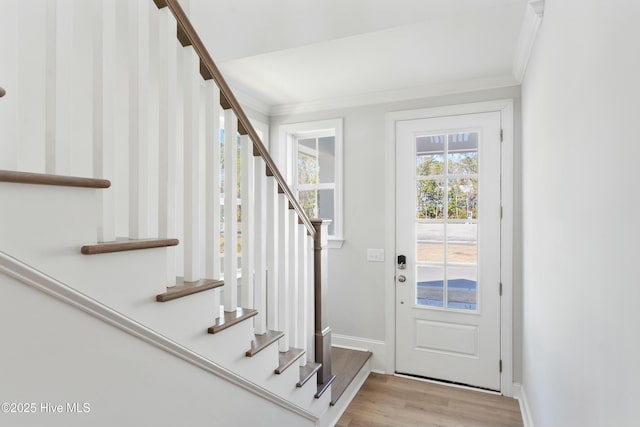 foyer entrance featuring stairs, baseboards, crown molding, and wood finished floors