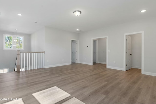 empty room featuring a chandelier, recessed lighting, light wood-style flooring, and baseboards