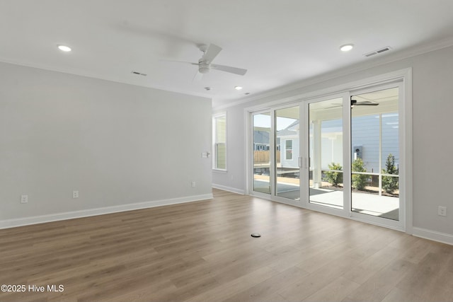 unfurnished room with visible vents, ornamental molding, a ceiling fan, wood finished floors, and baseboards