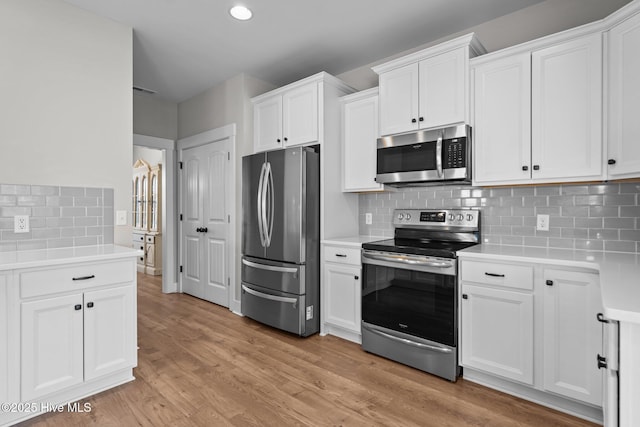 kitchen with light wood-type flooring, white cabinetry, stainless steel appliances, and light countertops