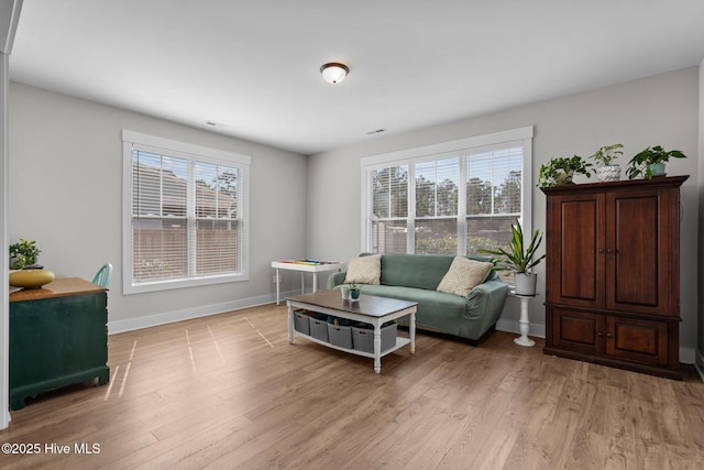 living area with light wood finished floors, visible vents, and baseboards