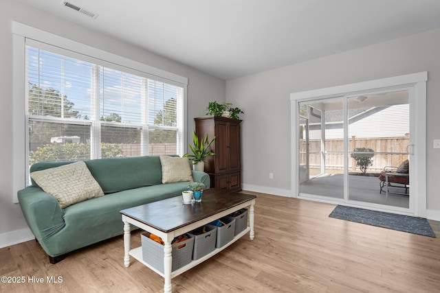 living area featuring light wood-style floors, visible vents, and baseboards