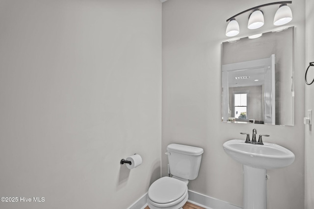 bathroom with baseboards, a sink, visible vents, and toilet