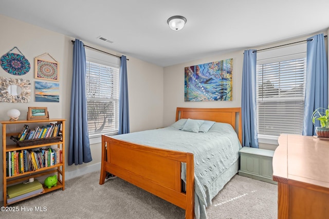 bedroom with baseboards, visible vents, and light colored carpet