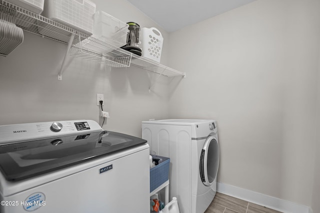 clothes washing area with light wood-style floors, washing machine and dryer, laundry area, and baseboards