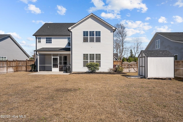 rear view of house with a fenced backyard, an outdoor structure, a sunroom, a lawn, and a storage unit