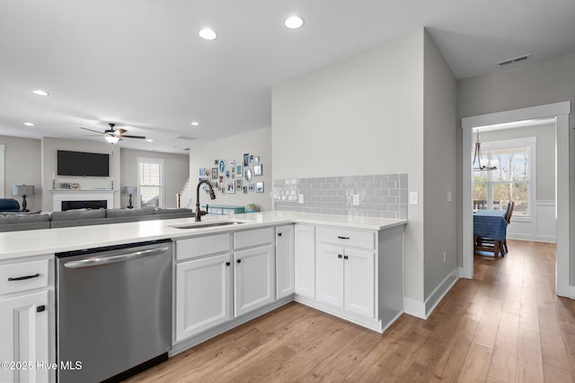 kitchen featuring white cabinets, a sink, light wood-style flooring, and stainless steel dishwasher