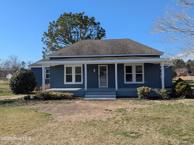 view of front of property featuring roof with shingles, a porch, and a front yard