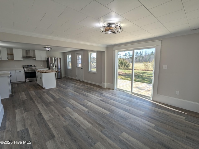 kitchen featuring a center island, dark wood-style flooring, crown molding, stainless steel appliances, and wall chimney exhaust hood